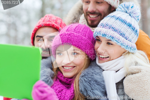 Image of smiling friends with tablet pc in winter forest