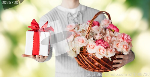 Image of man holding basket full of flowers and gift box