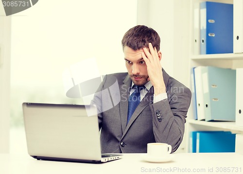 Image of busy businessman with laptop and coffee