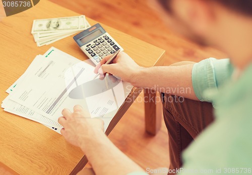 Image of close up of man counting money and making notes