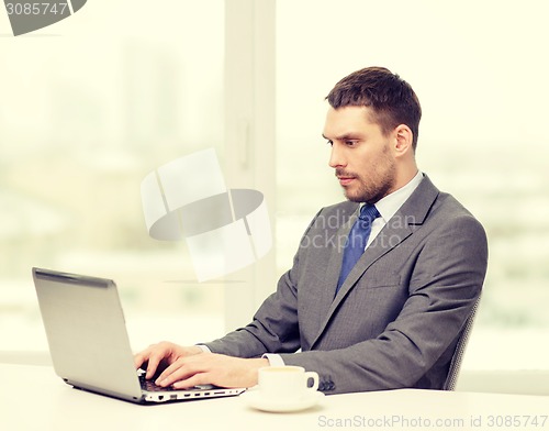 Image of busy businessman with laptop and coffee