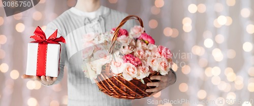 Image of man holding basket full of flowers and gift box