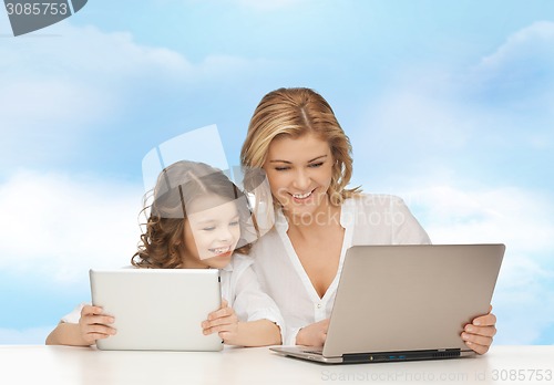 Image of mother with girl looking to laptop and tablet pc