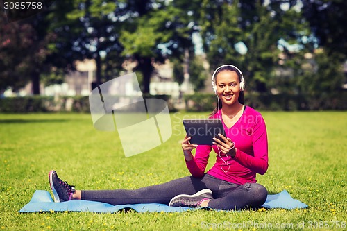 Image of smiling woman with tablet pc outdoors