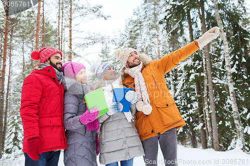 Image of smiling friends with tablet pc in winter forest