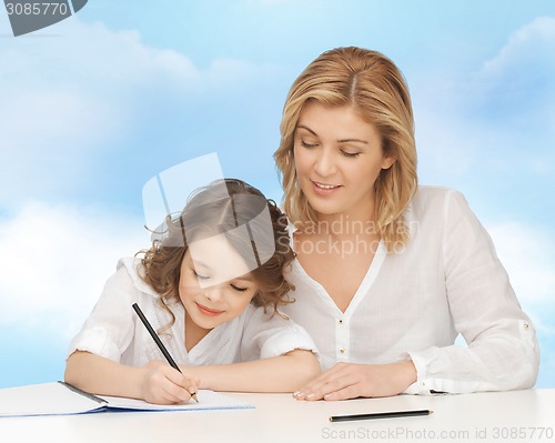 Image of happy mother and daughter writing in notebook