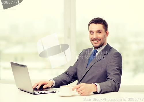 Image of smiling businessman with laptop and coffee