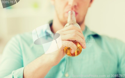 Image of close up of man drinking beer at home