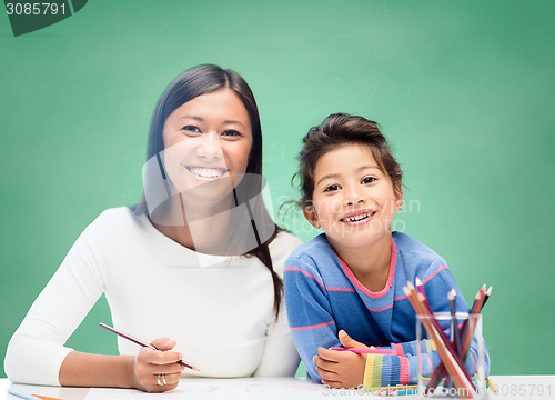 Image of happy teacher and little schoolgirl drawing