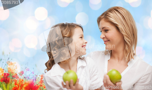 Image of happy mother and daughter with green apples