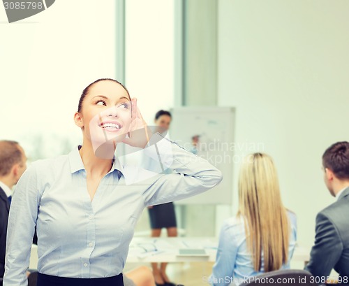 Image of smiling businesswoman listening gossig