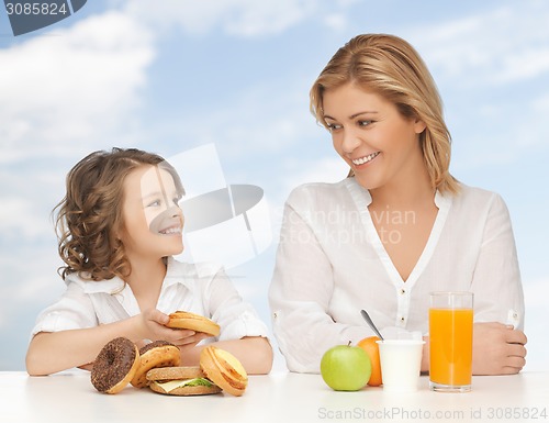 Image of happy mother and daughter eating breakfast