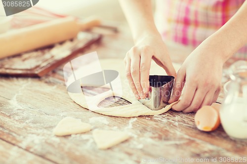 Image of close up of hands making cookies from fresh dough