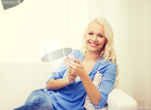 Image of smiling woman with smartphone at home