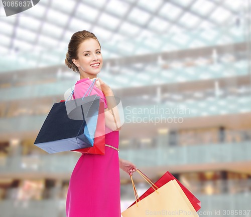 Image of young happy woman with shopping bags over lights