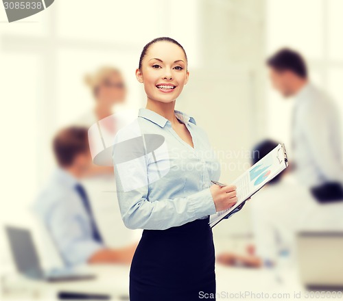 Image of young smiling businesswoman with clipboard and pen