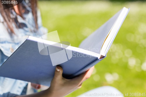Image of close up of young girl with book in park