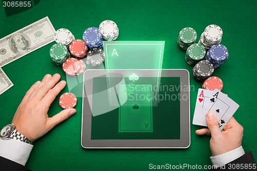 Image of casino poker player with cards, tablet and chips