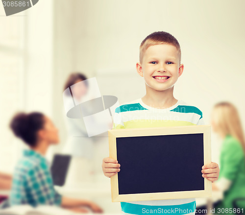 Image of smiling little boy holding blank black chalkboard