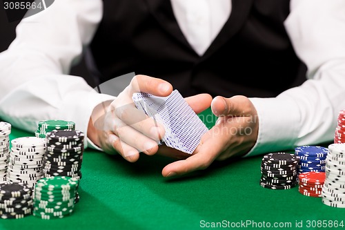 Image of holdem dealer with playing cards and casino chips