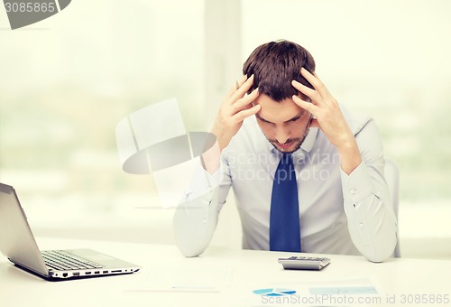 Image of stressed businessman with laptop and documents