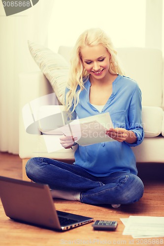 Image of smiling woman with papers, laptop and calculator