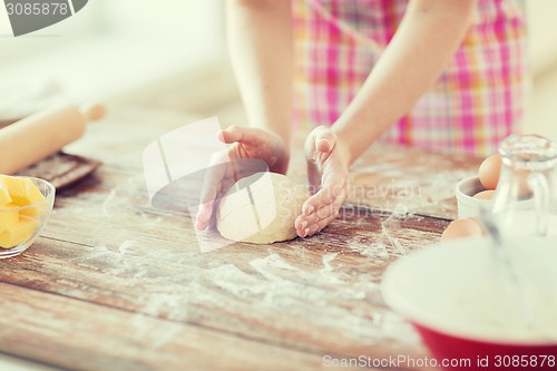 Image of close up of female hands kneading dough at home