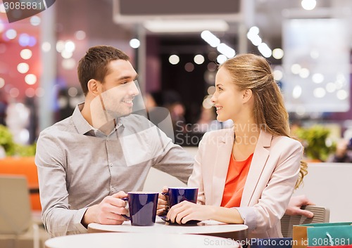 Image of happy couple with shopping bags drinking coffee