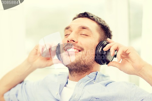 Image of smiling young man in headphones at home