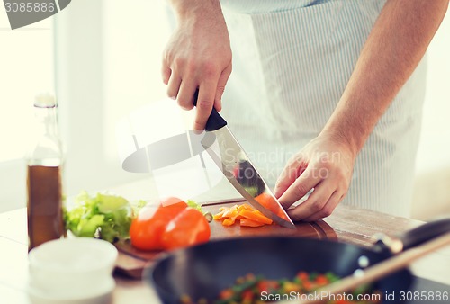 Image of close up of male hand cutting pepper on board