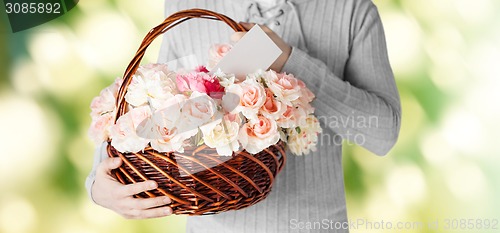 Image of man holding basket full of flowers and postcard