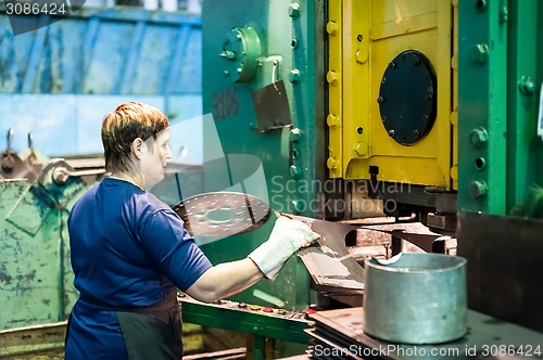 Image of Woman stamps details on hydraulic press