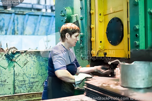 Image of Senior woman stamps details on hydraulic press