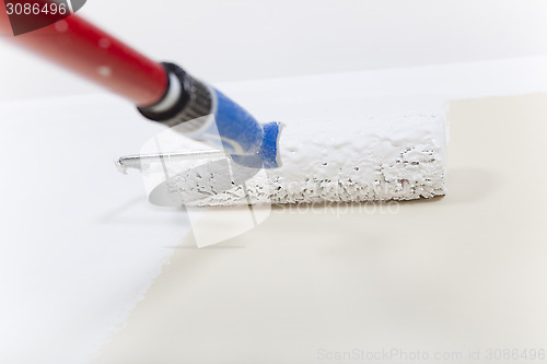 Image of Paint roller with white paint on wall