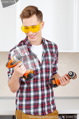 Image of smiling repairman in yellow safety glasses selects tool