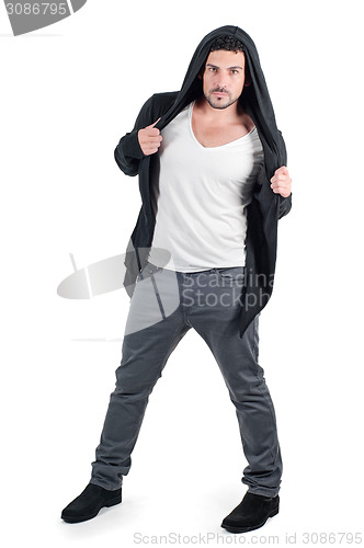 Image of Young man in black hooded jacket poses at studio