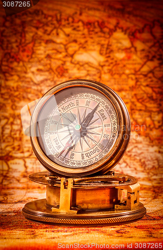 Image of Vintage compass lies on an ancient world map.