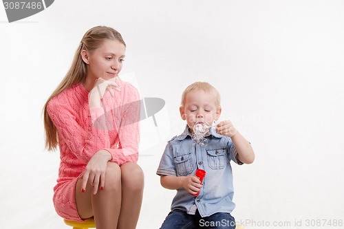 Image of Mom watches her son to blow bubbles