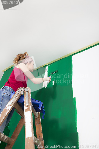 Image of Woman paints the wall green