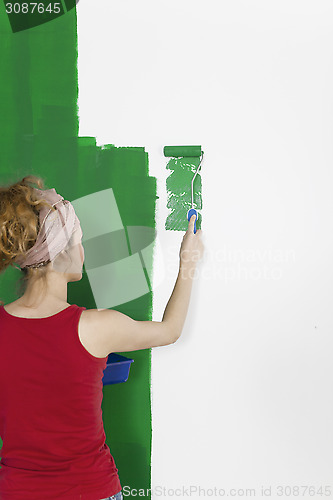 Image of A woman painting wall green