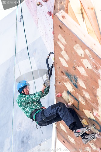 Image of Man climbs upward on ice climbing competition