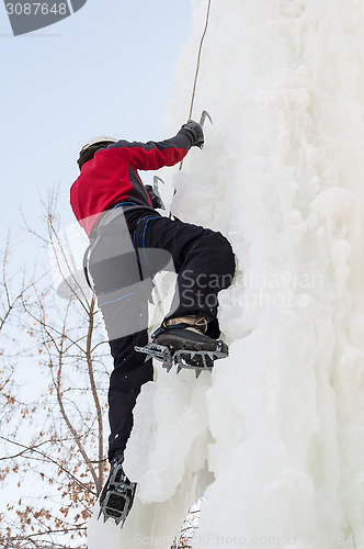 Image of Man climbs upward on ice climbing competition