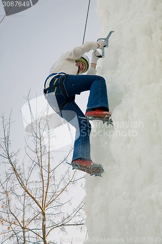 Image of Girl climbs upward on ice climbing competition