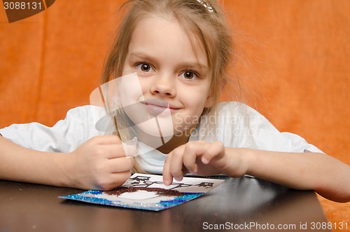 Image of The girl at table tinkering sand applique