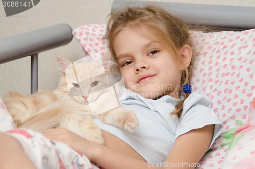 Image of Portrait of the girl with a cat lying in bed