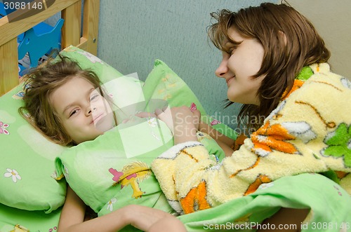Image of Mom wakes up her daughter in the morning