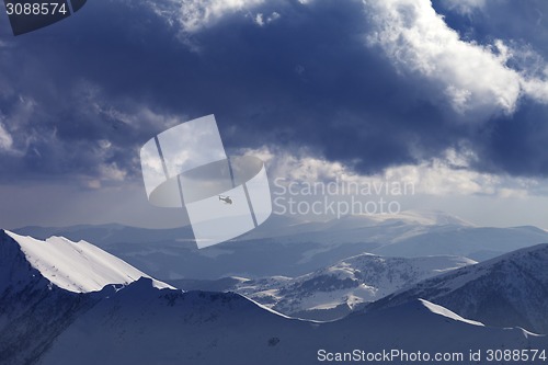 Image of Off-piste slope for heliskiing and helicopter in evening mountai