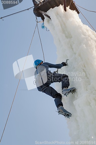 Image of Man climbs upward on ice climbing competition