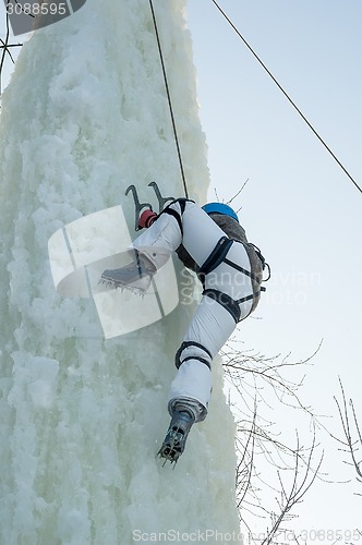 Image of Girl climbs upward on ice climbing competition