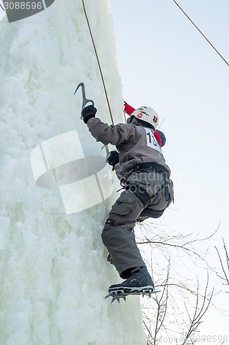 Image of Man climbs upward on ice climbing competition